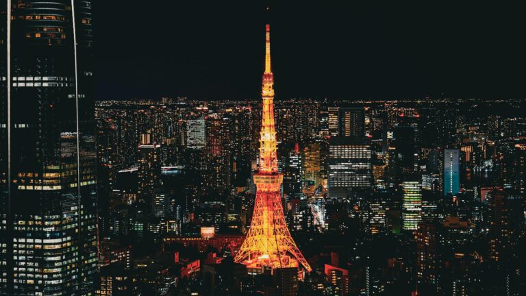 illuminated tokyo tower amidst tokyo skyline at night