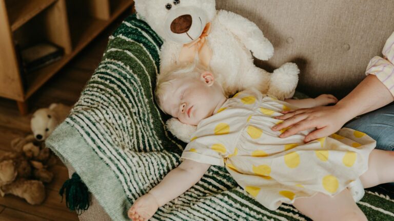 little girl sleeping beside a teddy bear